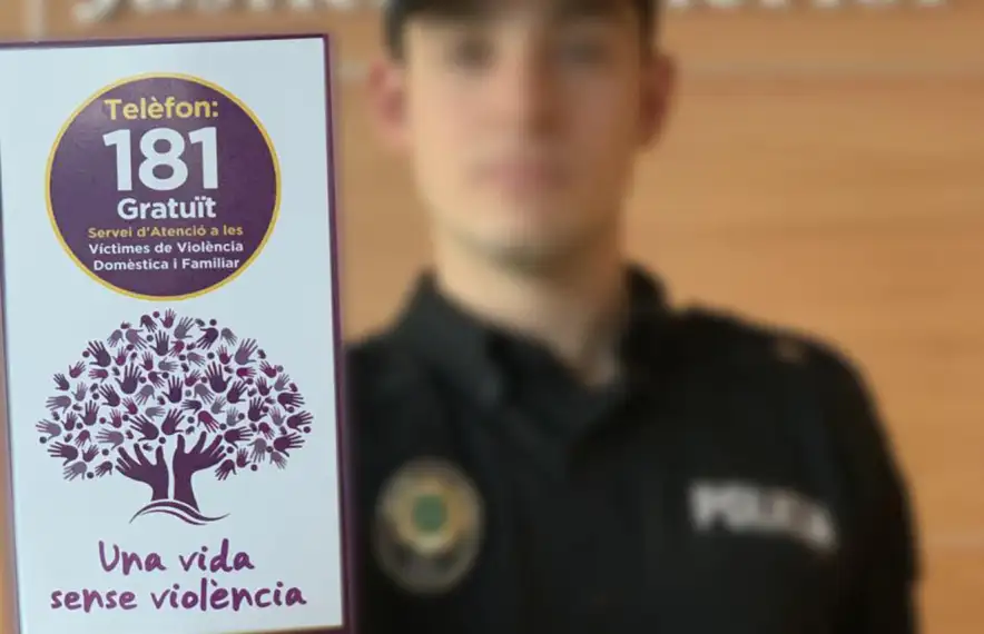 Un agent amb el fulletó que recorda el número d'atenció a les víctimes.