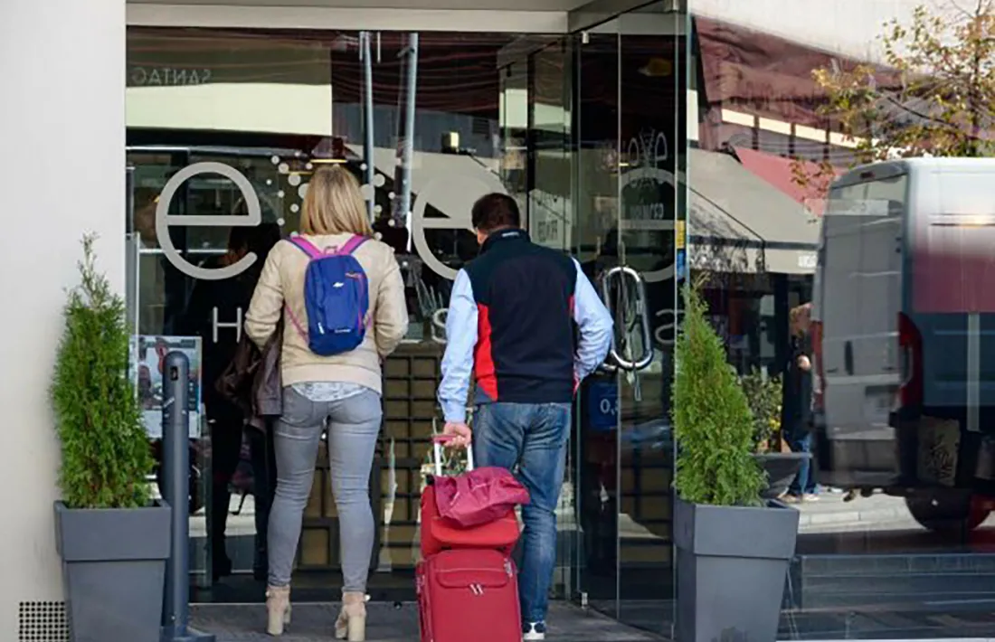 Dos turistes entren en un establiment hoteler.