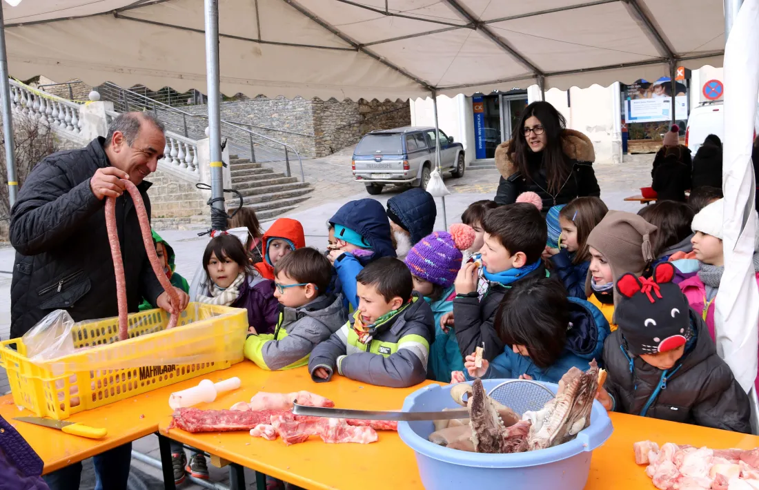 Un home mostra una llonganissa a un grup d’escolars.