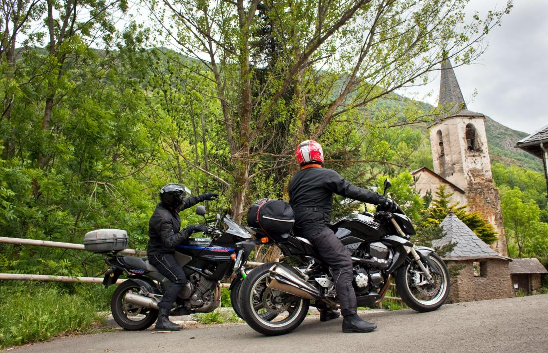 Dos motoristes mirant l’ermita d’Unarre, al Pallars Sobirà.