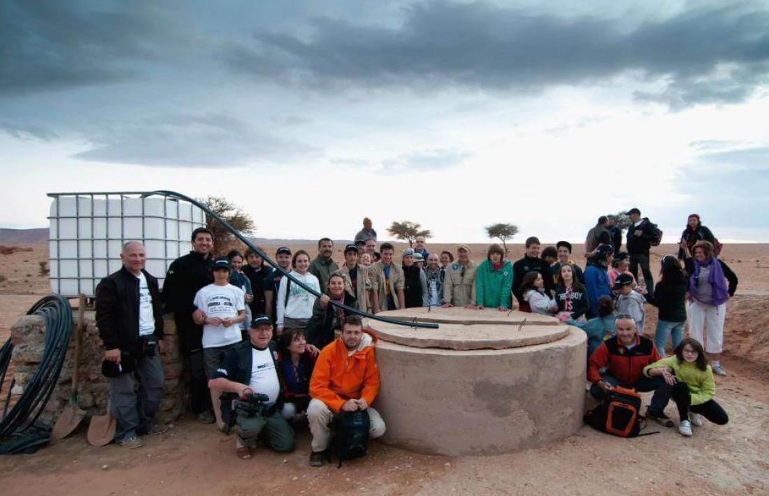 Participants del Raid Solidari i veïns d’Ouzina amb el pou d’aigua. 