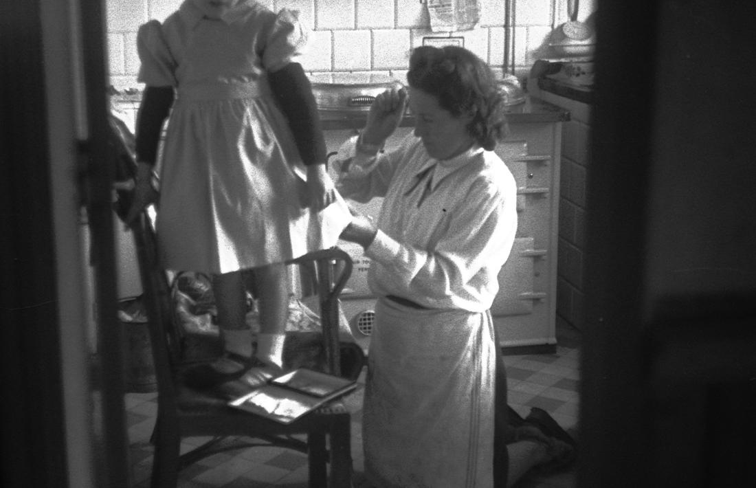 Anys 50: l'esposa de Josep Alsina cus la bata d'una veïneta enfilada a la cuina de la casa del fotògraf, a l'avinguda Carlemany d'Escaldes.