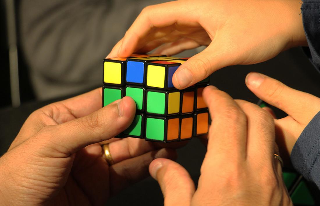 Diferents mans fent un cub de Rubik.