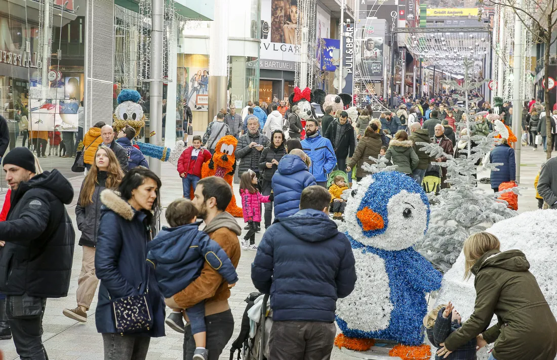 Els turistes omplen l’eix comercial i aprofiten per fer-se fotos amb la decoració nadalenca de fons.