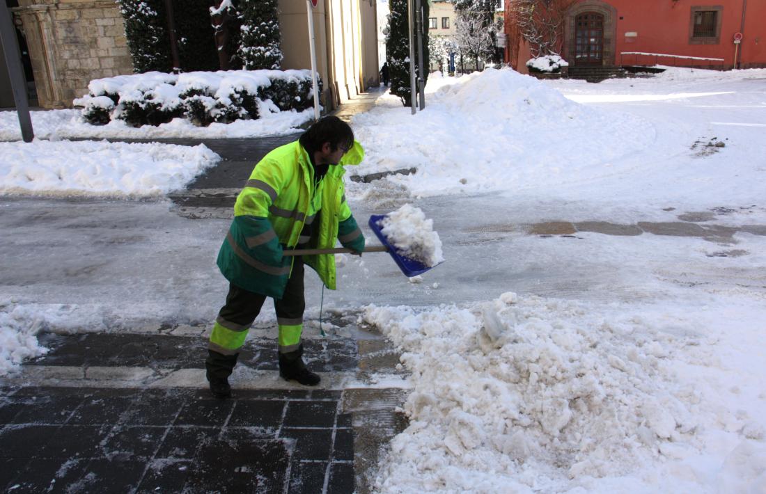 Un operari netejant la neu a la zona de la plaça dels Oms de la Seu.