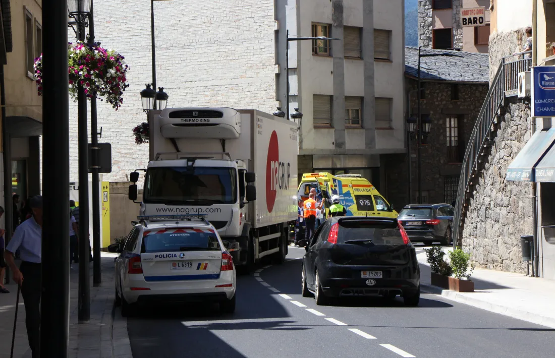 El camió estacionat al costat esquerre de la calçada i el vianant sortint de l'ambulància, en el lloc dels fets.