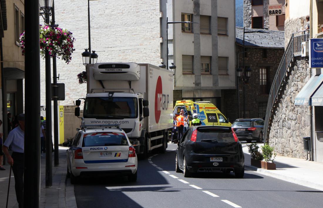El camió estacionat al costat esquerre de la calçada i el vianant sortint de l'ambulància, en el lloc dels fets.