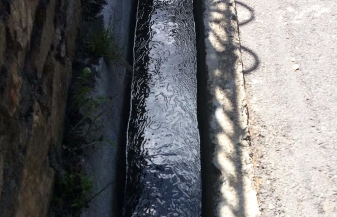 Taques d'hidrocarbur en un canal d'aigua, en un vessament anterior.