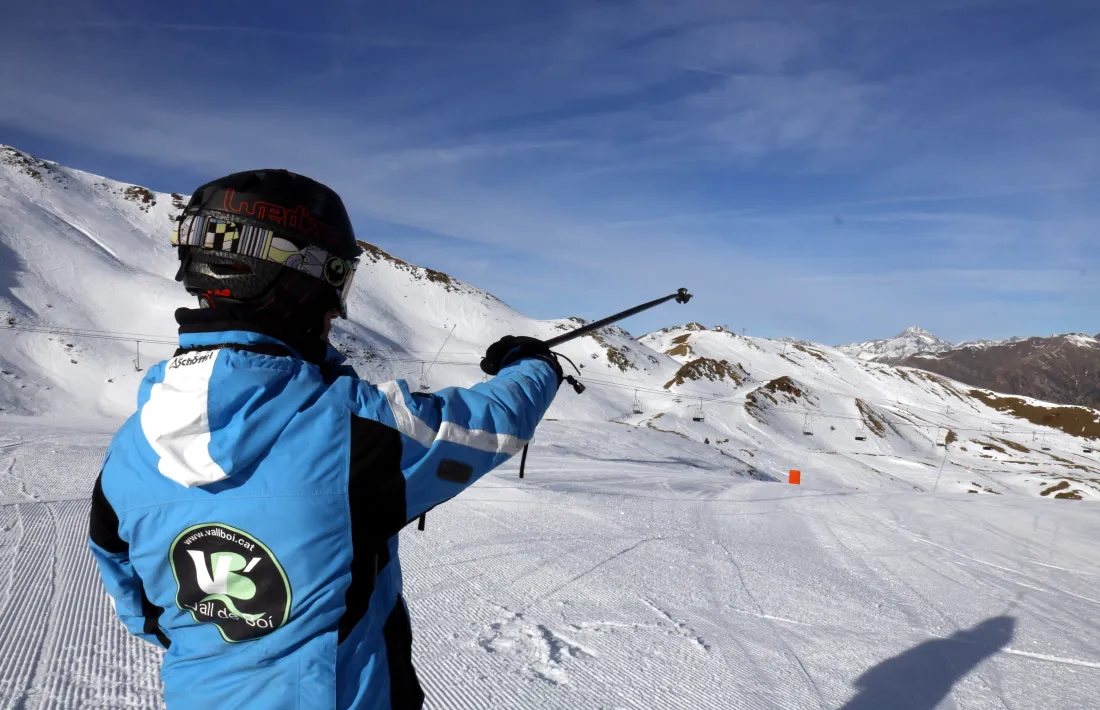 Un monitor de Boí Taüll assenyalant amb un bastó el paisatge.