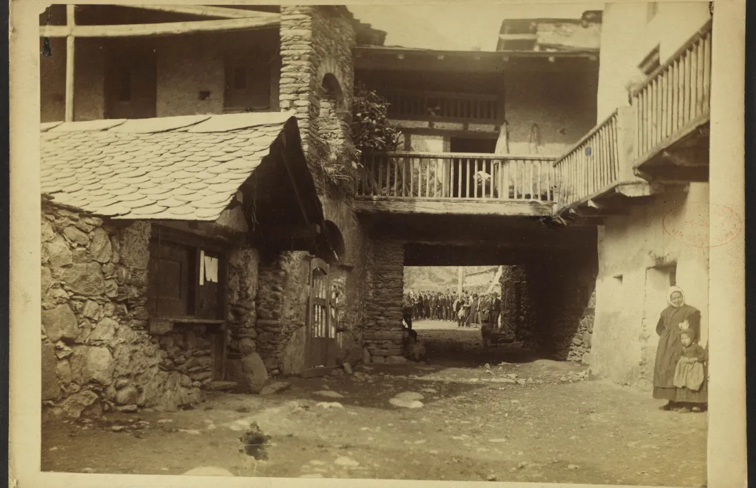 Carrer major de la Mosquera, de nou: en primer terme, a l'esquerra, la carnisseria comunal, amb tres bans penjats a la porta; al fons, els veïns posen per a la foto, ells al davant, i elles, al darrere.