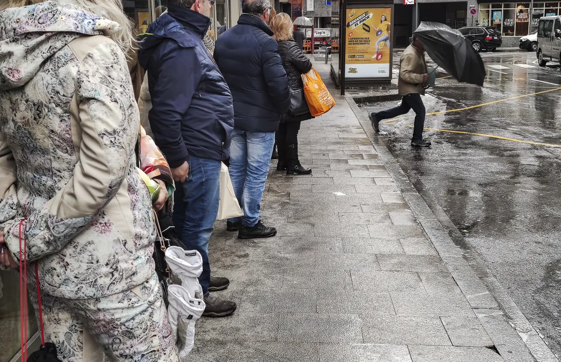Un grup de persones esperen l’autobús en una parada d’Andorra la Vella.