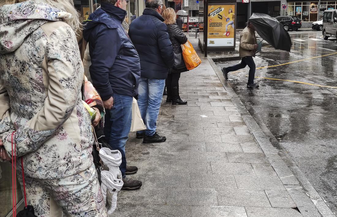 Un grup de persones esperen l’autobús en una parada d’Andorra la Vella.
