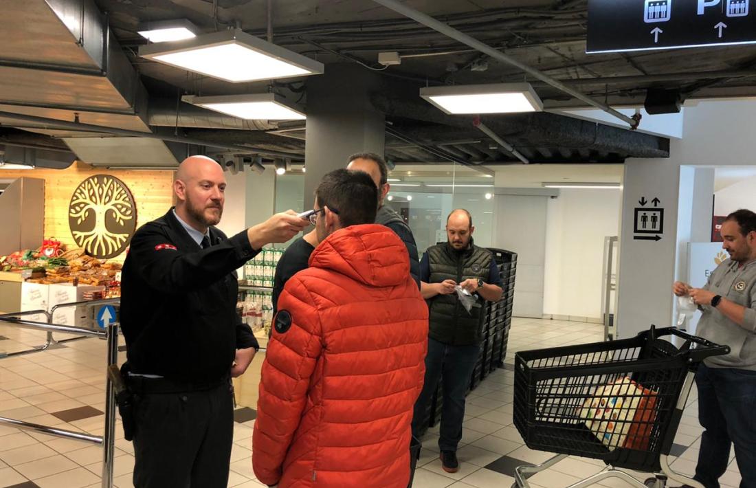 La seguretat de Pyrénnés pren la temperatura a un client abans d'entrar al supermercat.