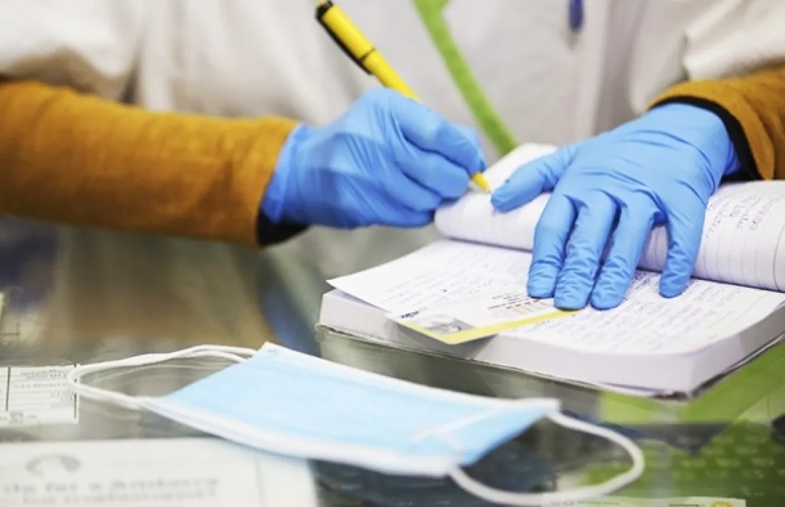 Un farmacèutic dispensa mascaretes a un client.
