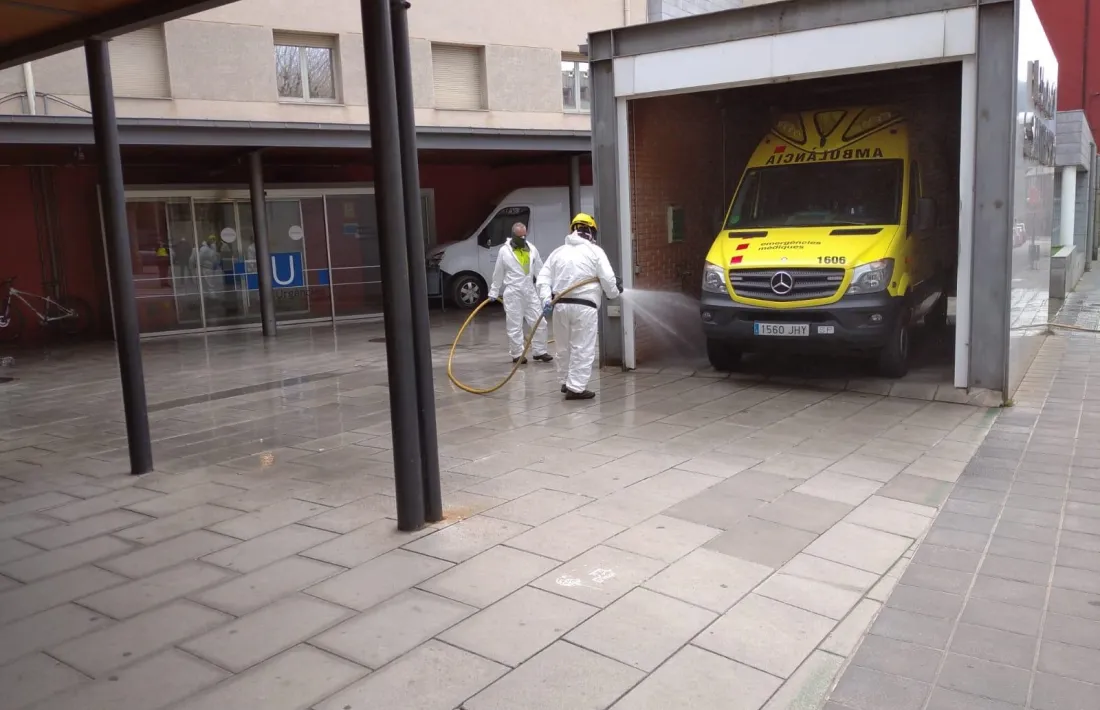 Dos funcionaris desinfectant l'exterior de l'hospital de la Seu.