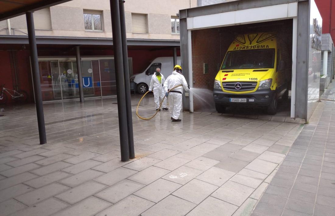 Dos funcionaris desinfectant l'exterior de l'hospital de la Seu.