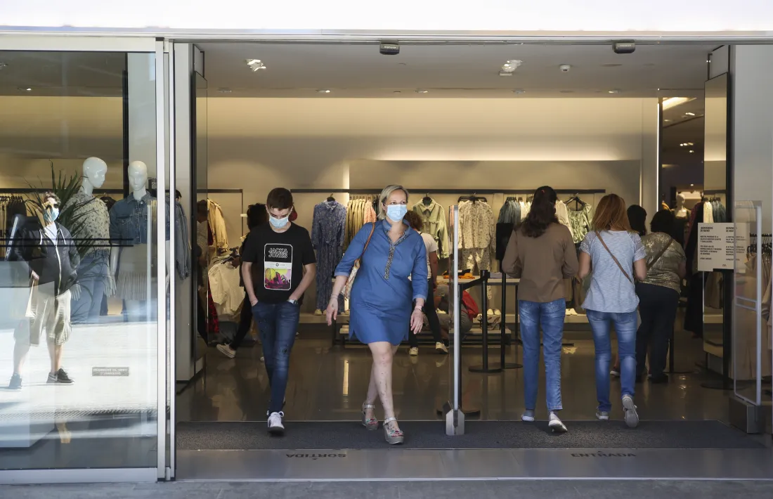 Clients amb mascareta surten d’un comerç de moda de la capital.