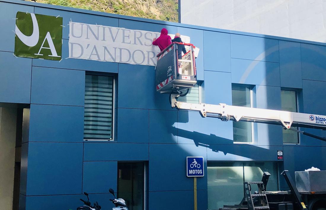 Uns operaris instal·len la retolació exterior de l’edifici Cub de la Universitat d’Andorra.