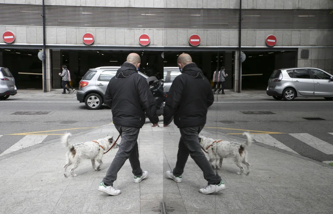 Un home passeja un gos pel centre d’Andorra la Vella.