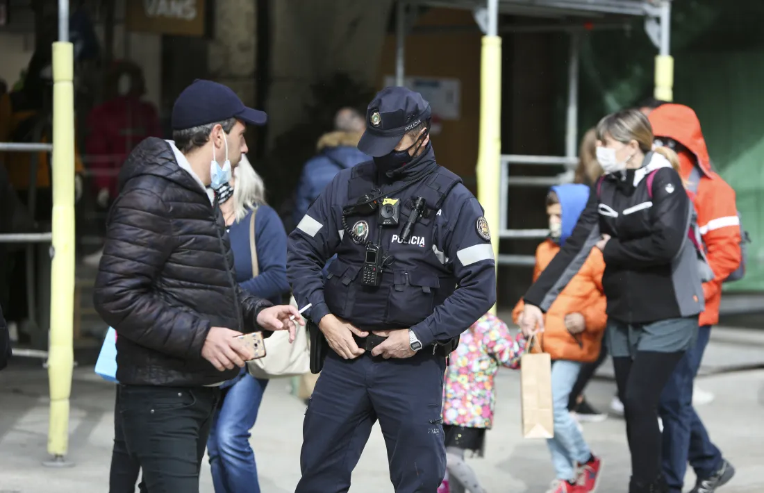 Un agent de policia informa un turista que no pot fumar i estar sense mascareta al mig del carrer.
