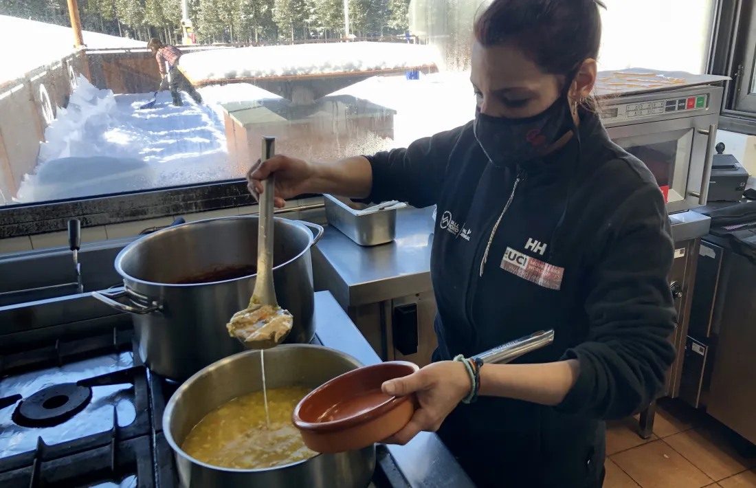 Una cuinera prepara una ració d'escudella per servir-la.
