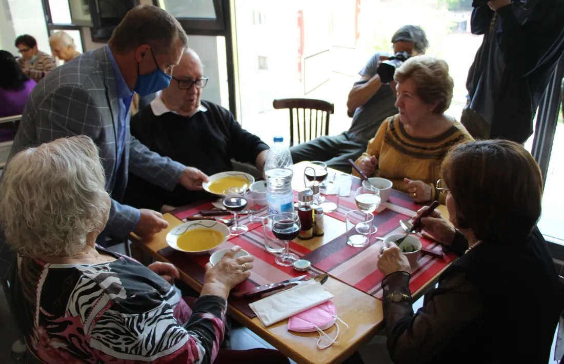 El cònsol major, Josep Majoral, serveix el dinar a alguns dels usuaris del menjador social.