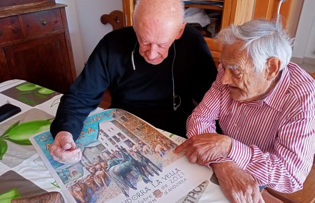 Casimir Arajol i Sergi Mas comenten el cartell d’aquest any, acabat de sortir de la impremta. L’original és a tinta xinesa i aquarel·la.