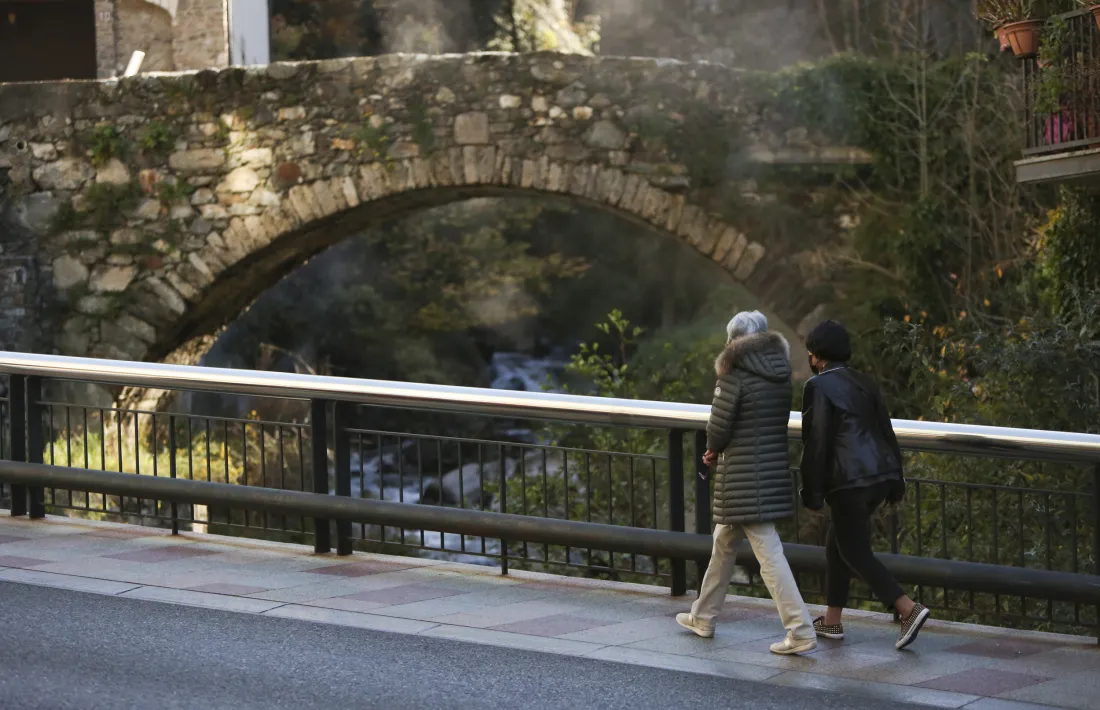 Dues persones caminen per davant del pont de la Tosca.