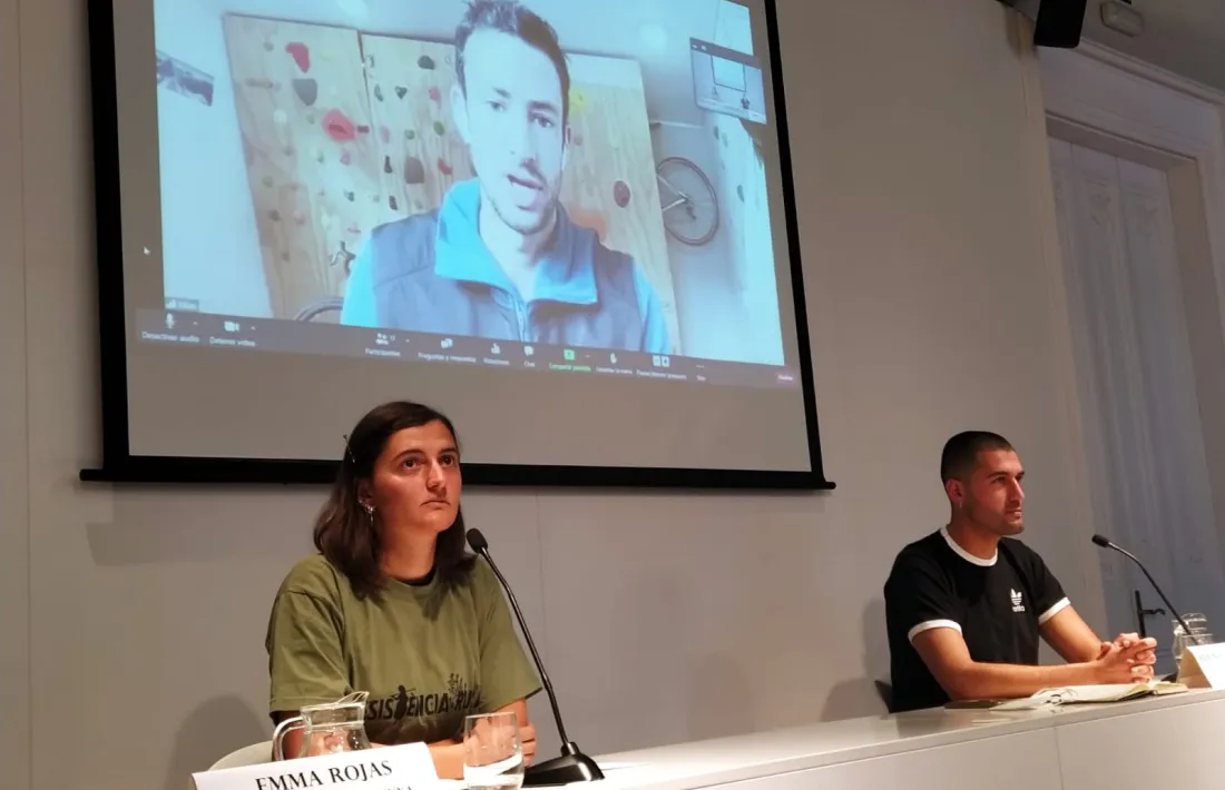 Emma Rojas i Bernat Lavaquiol, portaveus de la Plataforma Stop Jocs Olímpics. L’atleta Kilian Jornet a la pantalla.