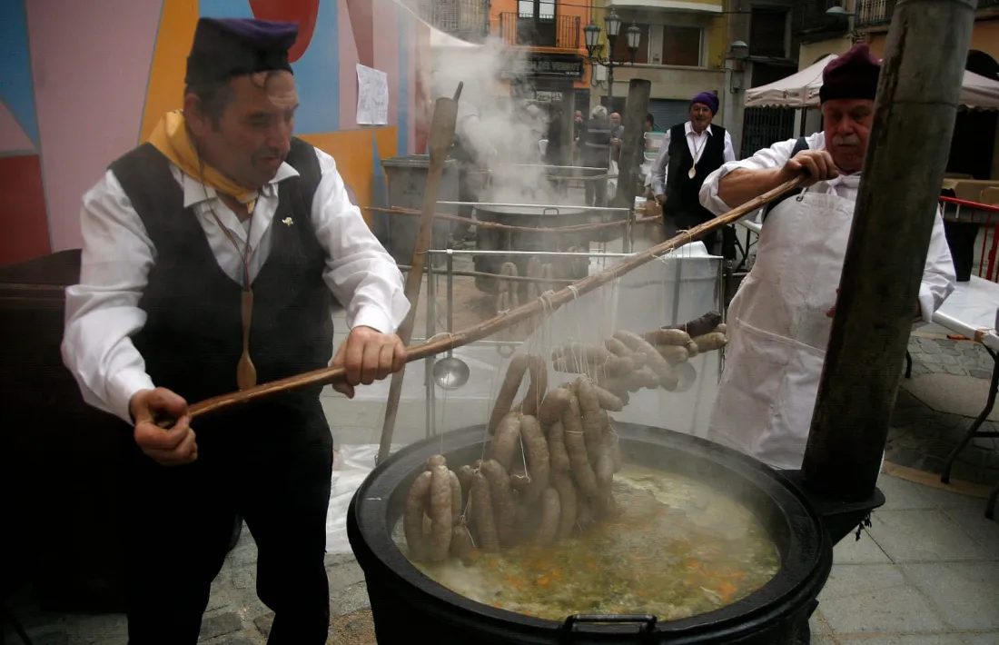 Dos escudellaires posant la botifarra a l'escudella.