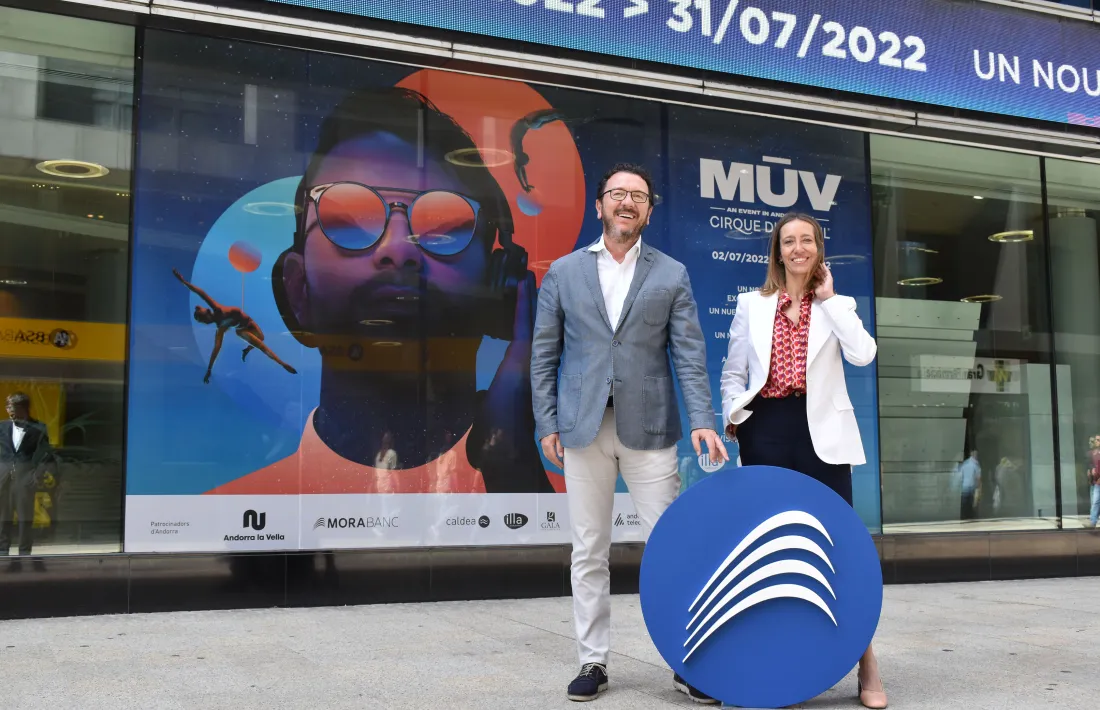 El gerent d'Andorra Turisme, Betim Buzaku, i la directora de Màrqueting i Marca de MoraBanc, davant del vinil de l'espectacle del Cirque du Soleil a la façana de l'entitat, que patrocina l'espectacle.