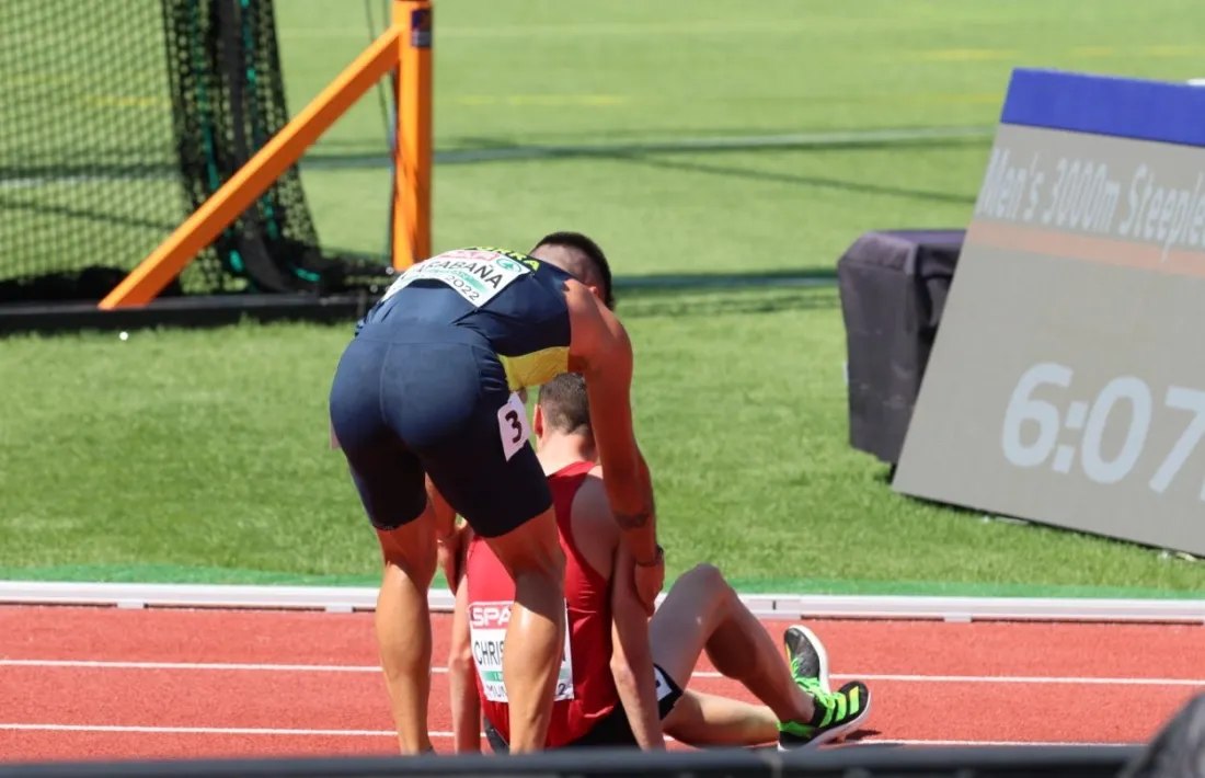 Nahuel Carabaña ajuda a aixecar-se l’atleta danès Axel Vang Christensen, que va ensopegar amb un dels obstacles de la prova dels 3.000 metres.