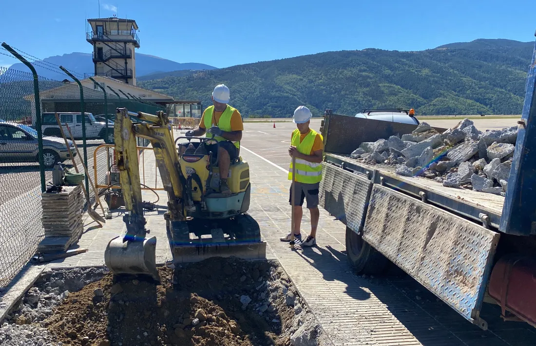 Dos operaris iniciant els treballs per instal·lar torres d’il·luminació a l’aparcament de l’aeroport Andorra-La Seu d’Urgell.