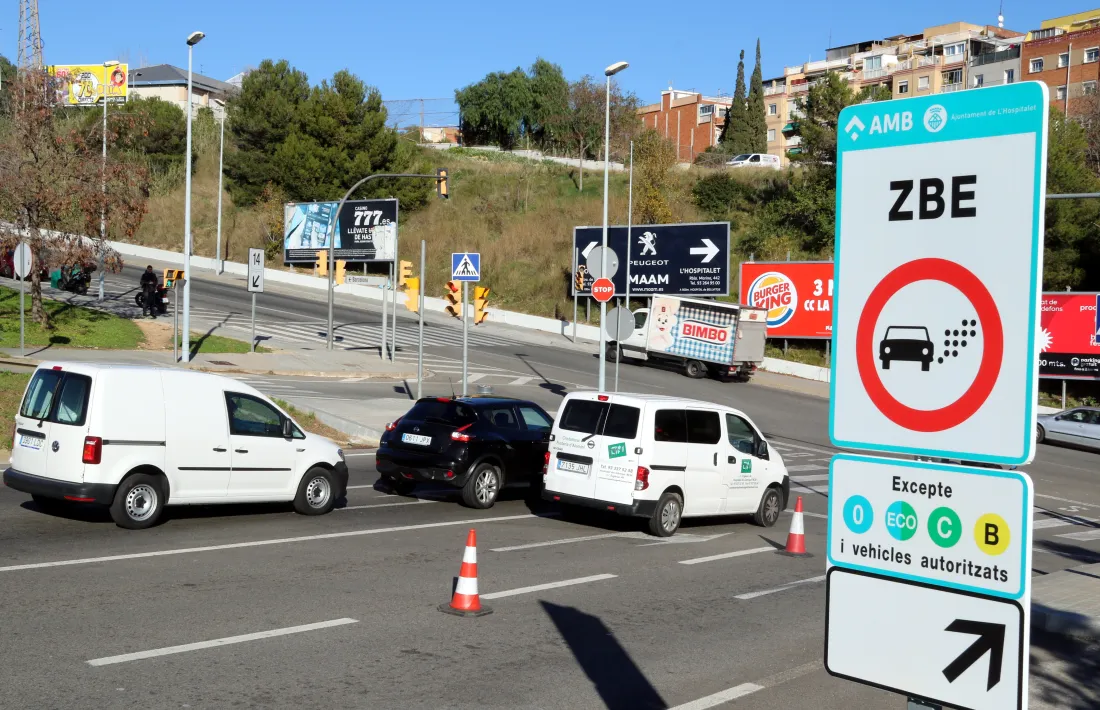 Vehicles passant pel costat d'un cartell indicatiu de la ZBE.