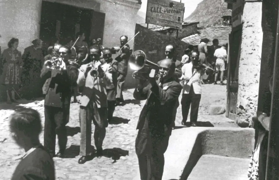És festa major i som als anys 40, i la banda desfila per la placeta de Santa Anna. Al fons, el pont d’Engordany, i a l’esquerra, l’hotel Pla.