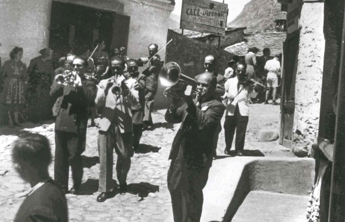 És festa major i som als anys 40, i la banda desfila per la placeta de Santa Anna. Al fons, el pont d’Engordany, i a l’esquerra, l’hotel Pla.