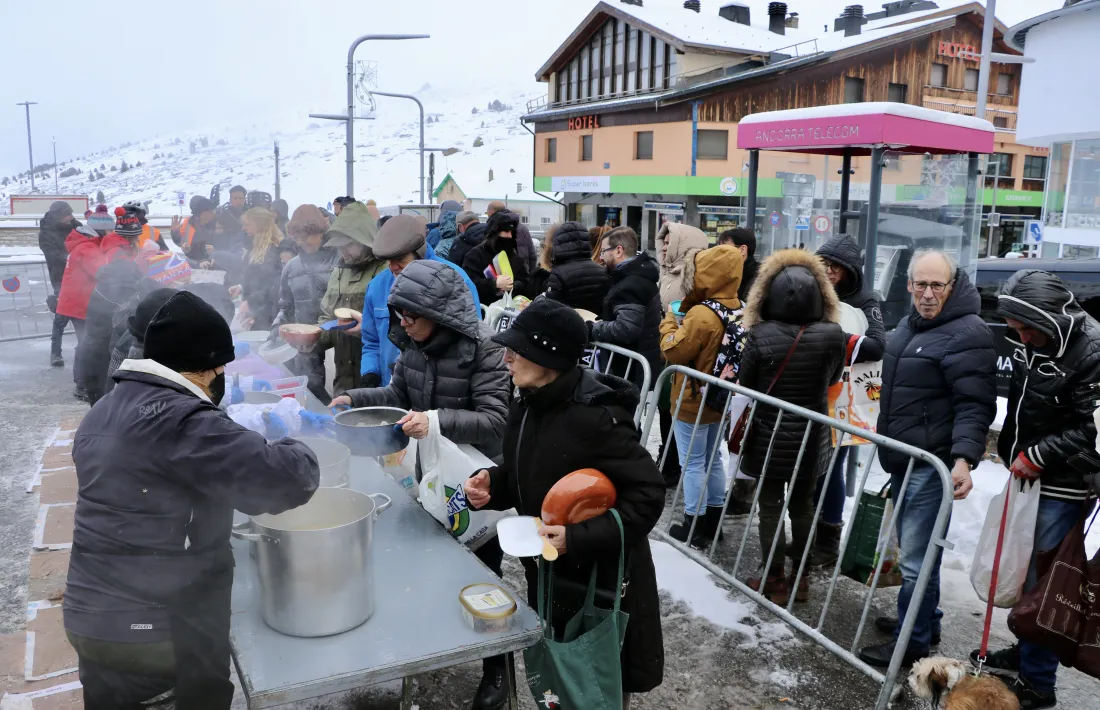 Veïns i visitants recollint la seva ració d’escudella.