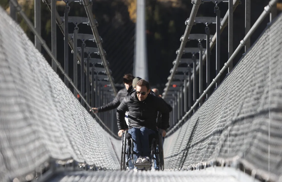 Un usuari amb cadira de rodes travessant el pont tibetà.