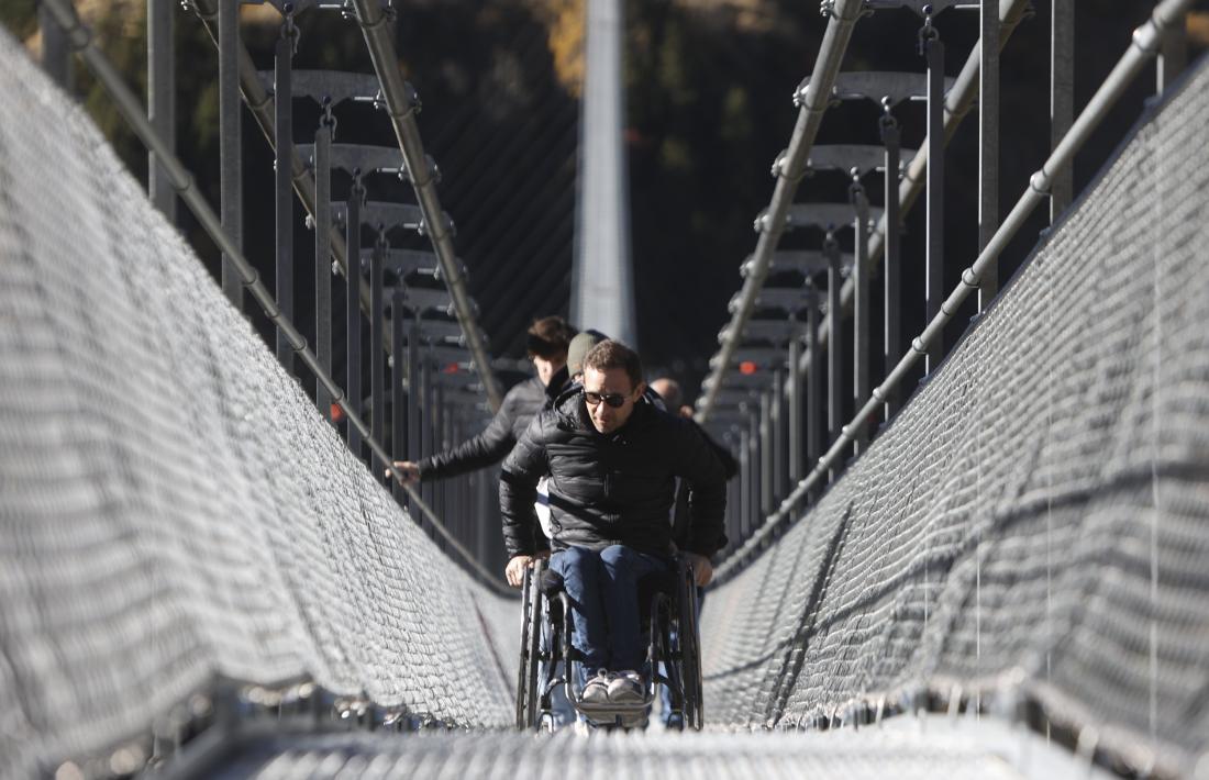 Un usuari amb cadira de rodes travessant el pont tibetà.