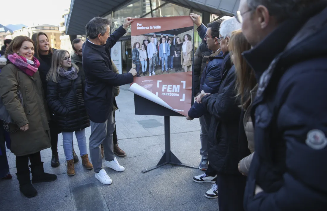 David Astrié i Miquel Canturri enganxen el cartell de Demòcrates+SDP+Independents davant la mirada de la resta d’integrants de la candidatura. 