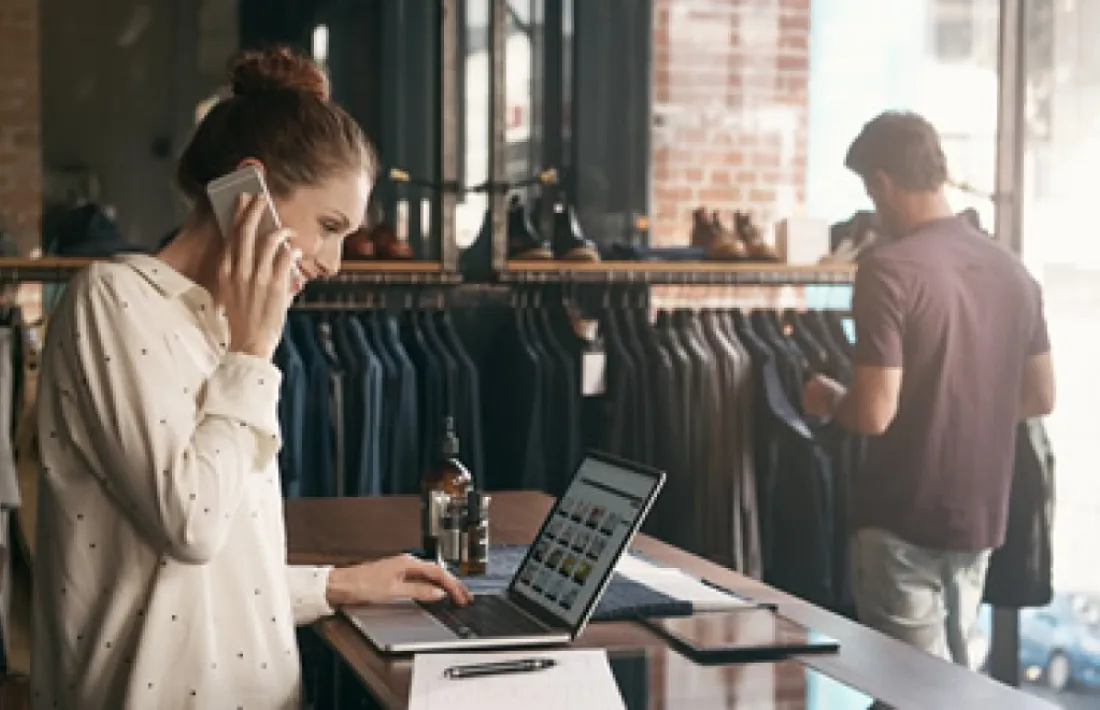 Una treballadora fent ús d'un ordinador i un telèfon.