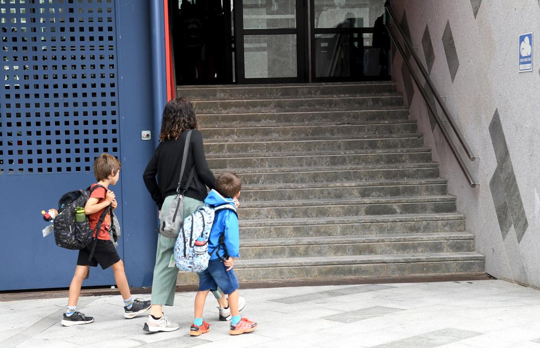 Una mare acompanya dos fills a l'escola.