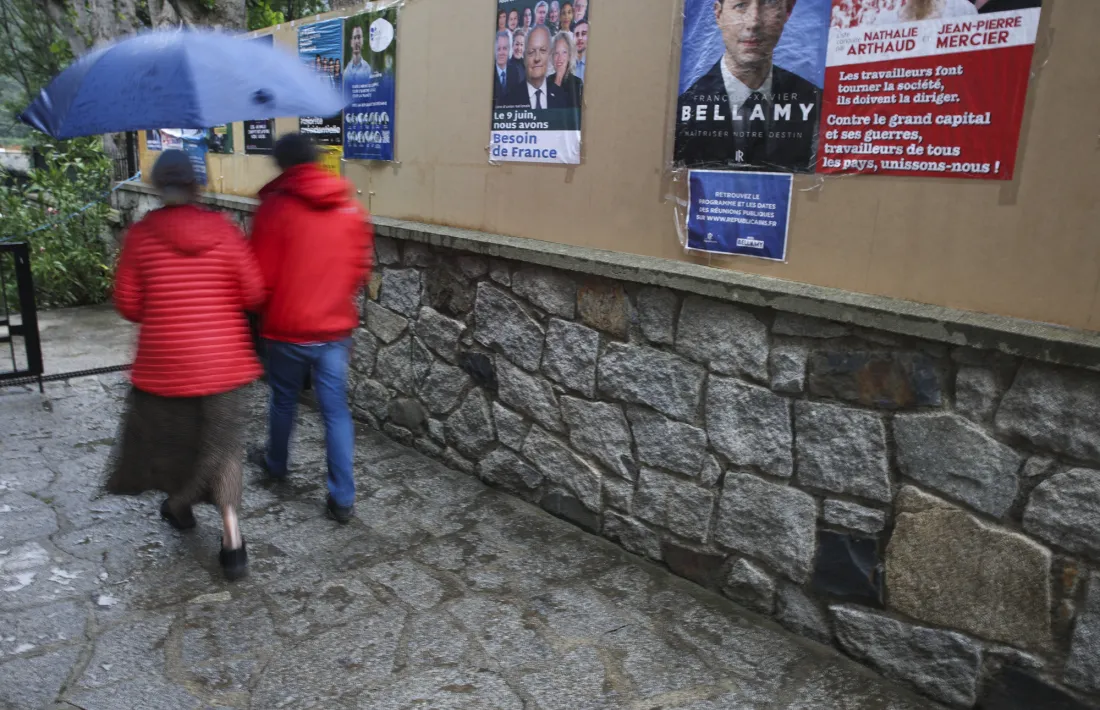Dos electors passant per davant dels cartells electorals a l’Ambaixada de França.