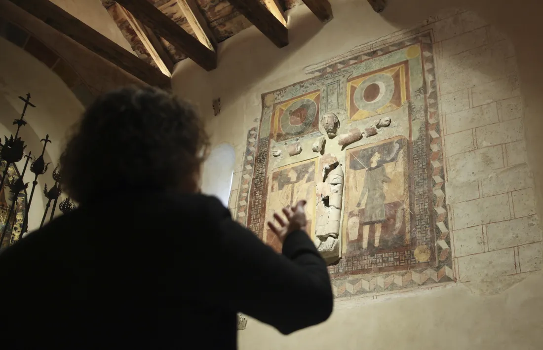 Cinta Pujal assenyala el Crist en estuc de Sant Joan de Caselles, ja completament restarat.