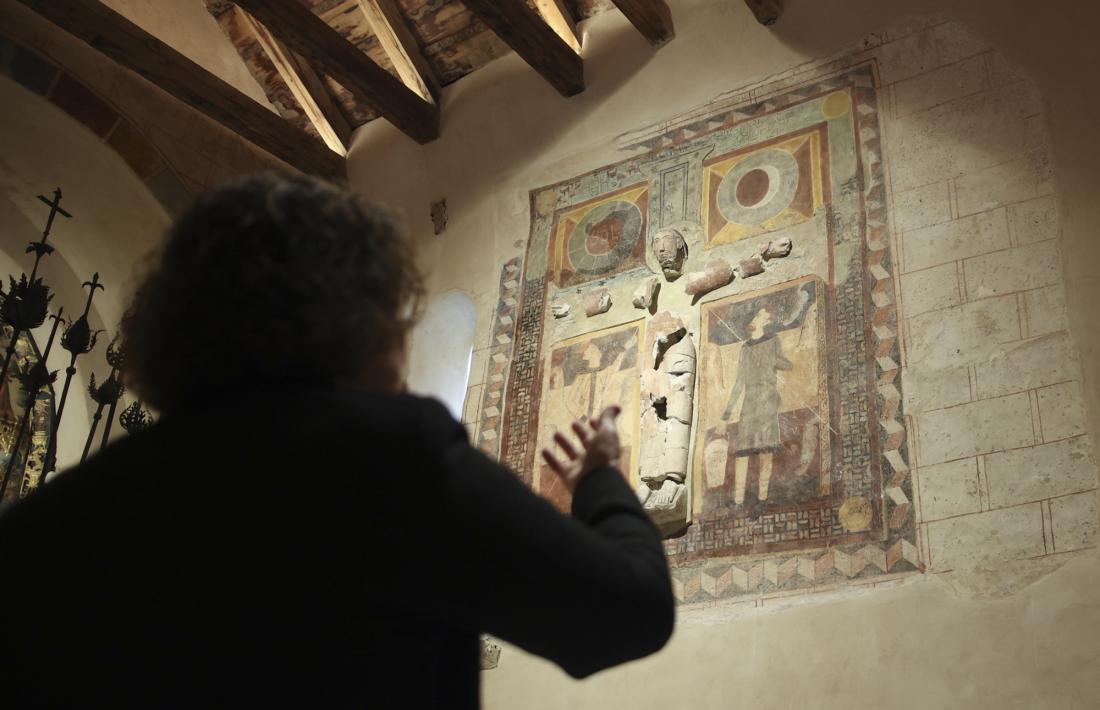 Cinta Pujal assenyala el Crist en estuc de Sant Joan de Caselles, ja completament restarat.