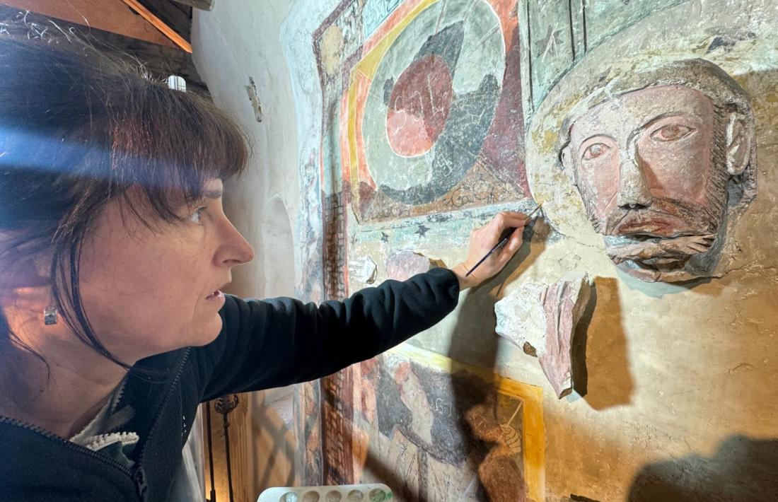 La restauradora Mireia Tarrés, enfilada la bastida que durant un mes ha cobert el Crist canillenc.