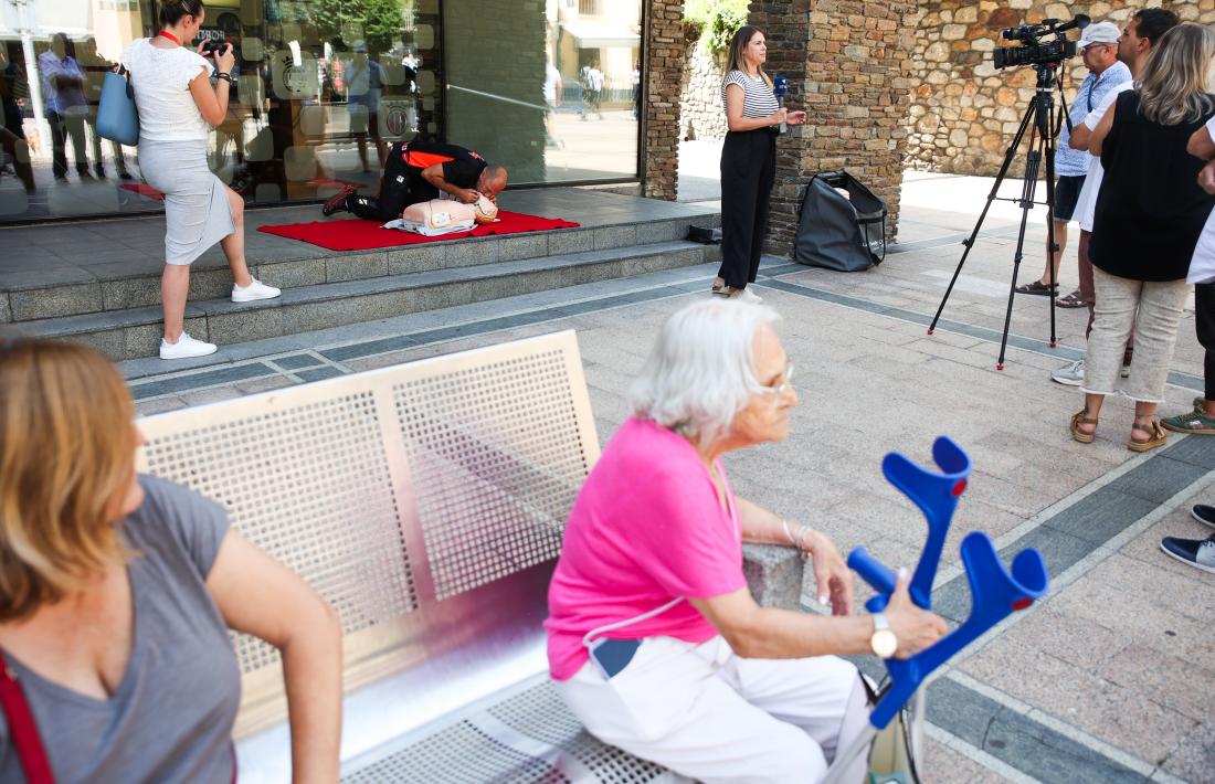 Al fons, Tolo fent la demostració de l’ús del desfibril·lador sota la mirada d’alguns curiosos.
