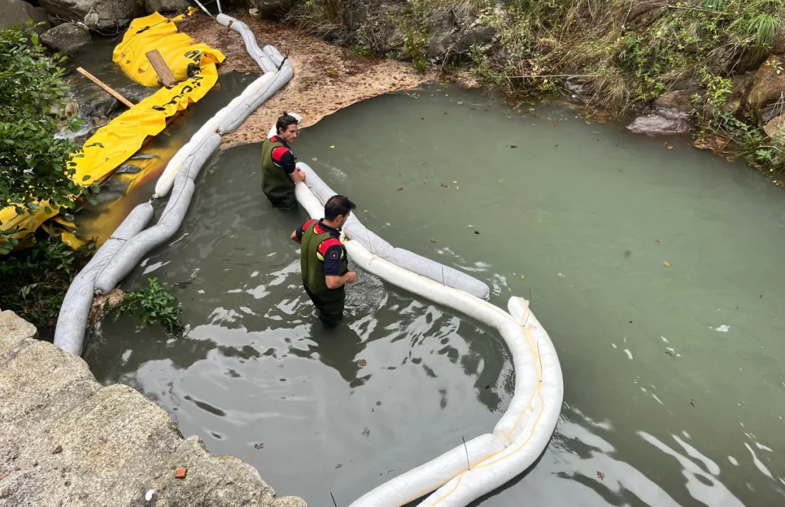 Bombers treballant per mirar de minimitzar l'impacte de la fuita d'hidrocarbur al riu Valira.