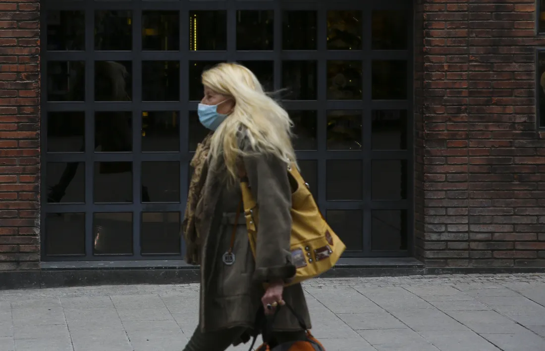 Una persona caminant protegint-se amb una mascareta.
