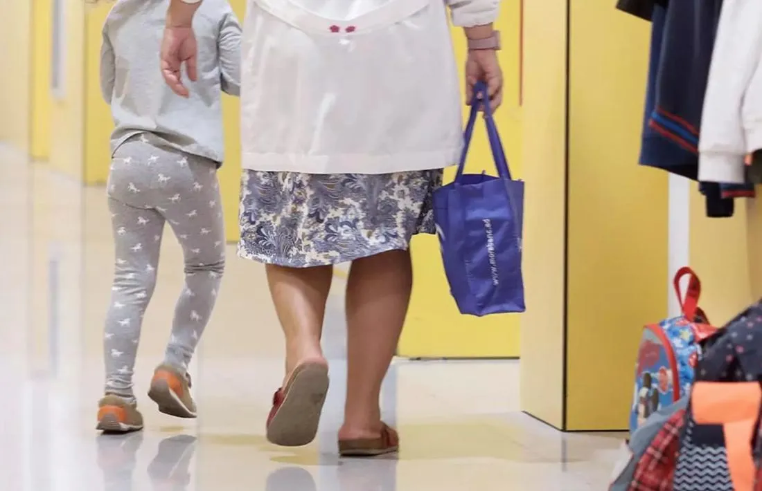 Una menor acompanyada per una persona adulta a un centre escolar.